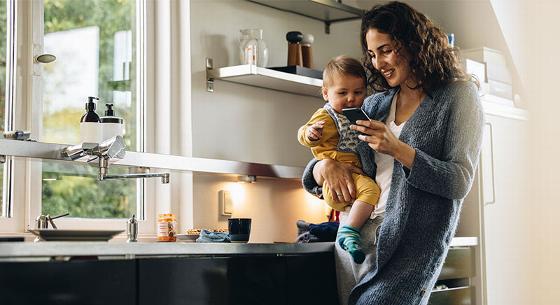 lady carrying baby while looking at phone